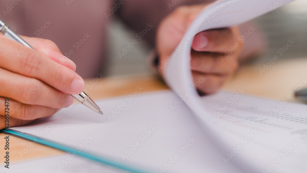Engaging in Document Review, Focused individual reviews important documents, process of careful examination and note-taking with pen in hand Engaging in Document Review, Focused individual reviews important documents, process of careful examination and note-taking with pen in hand