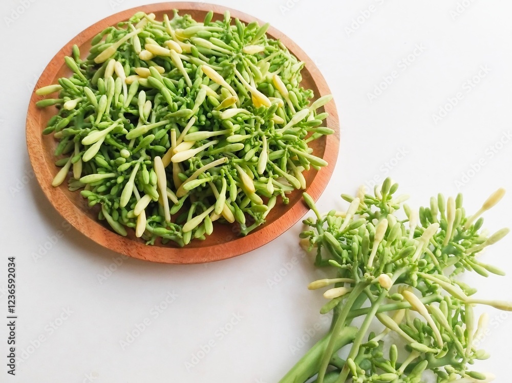 High angle view of uncooked papaya flower vegetables in a wooden plate on a white background. High angle view of uncooked papaya flower vegetables in a wooden plate on a white background.