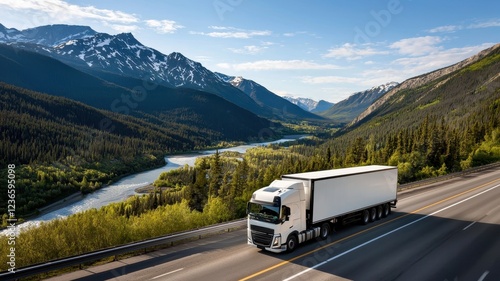 Scenic view of a truck driving along a highway with mountains and a river in the background. photo