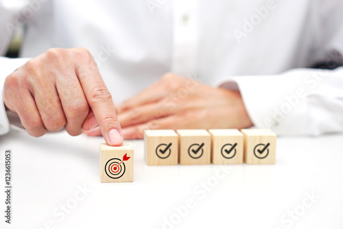 Hand touching a wooden block cube with target icon symbol. Business strategy and target of business.