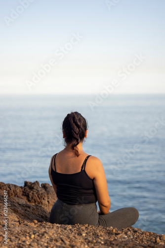 Chica mirando horizonte desde acantilado sobre el mar