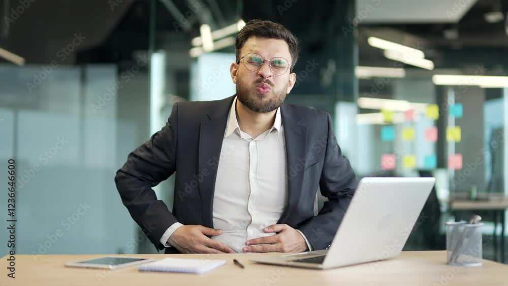 Sick businessman in a formal suit feels stomach pain working on laptop sitting at workplace in business office. Worker has heartburn, gastritis or poisoning. Male suffers from spasms and constipation Sick businessman in a formal suit feels stomach pain working on laptop sitting at workplace in business office. Worker has heartburn, gastritis or poisoning. Male suffers from spasms and constipation