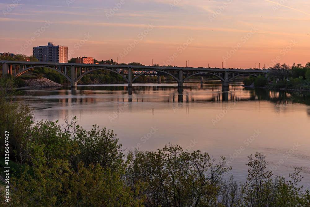 Obraz premium A bridge spans a river with a beautiful sunset in the background