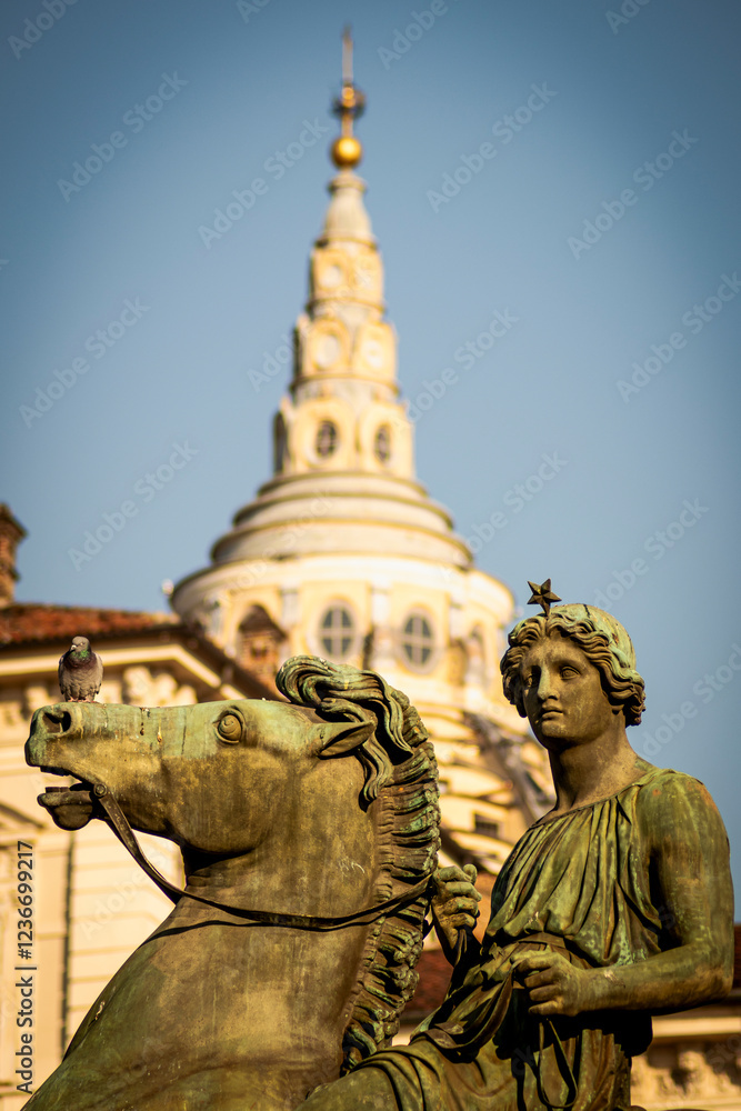 Fototapeta premium Turin, Italy. The entrance to the Royal square in front of the Royal Palace is watched by two bronze statues of the Dioscuri. Here with the Guarini's Dome of San Lorenzo in the background.