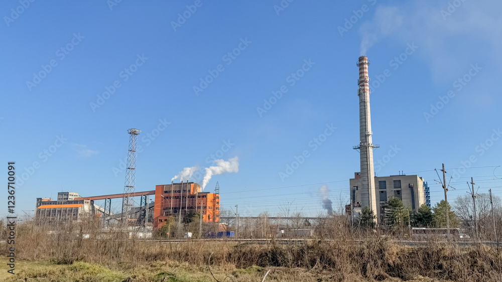 Industrial power plant emitting smoke against clear blue sky, highlighting environmental pollution and sustainability challenges Industrial power plant emitting smoke against clear blue sky, highlighting environmental pollution and sustainability challenges