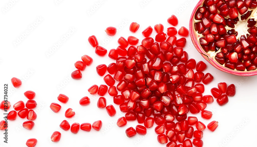 Bright red pomegranate seeds are scattered across a white surface alongside a halved pomegranate revealing its vibrant interior. The arrangement highlights the fruit's freshness and color Bright red pomegranate seeds are scattered across a white surface alongside a halved pomegranate revealing its vibrant interior. The arrangement highlights the fruit's freshness and color