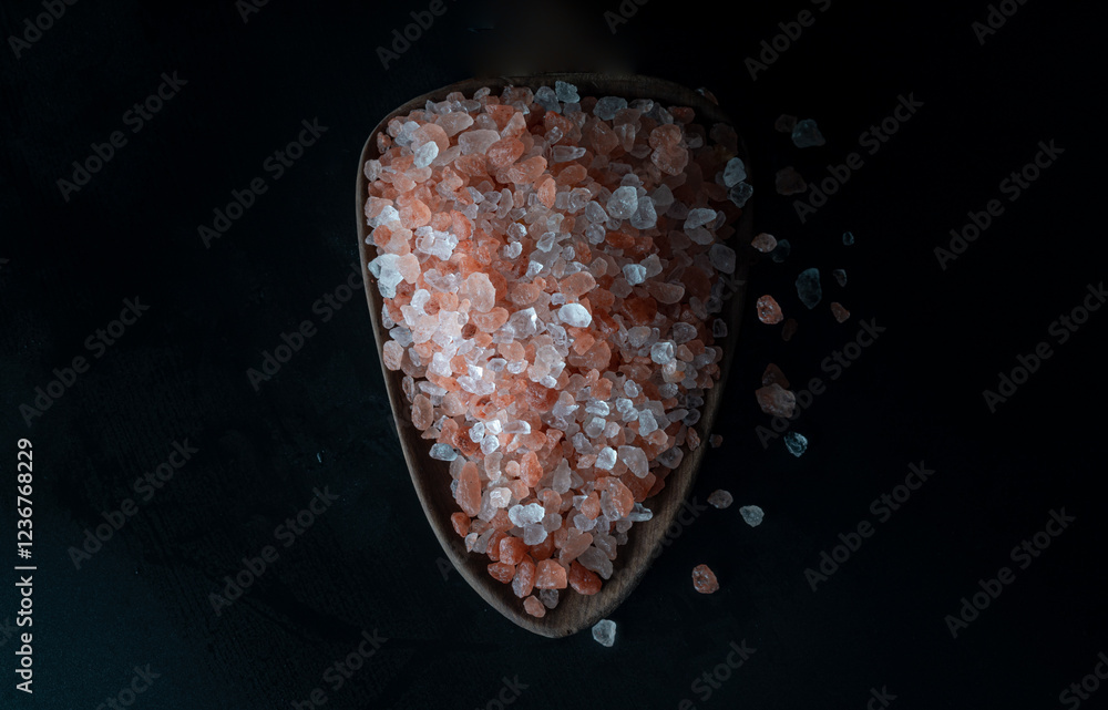 Top view of Pink Himalayan Salt with Bright colors textured surface on Wooden scoop with the dark background. Crystals and crushed blocks of natural pink salt, Chipped Himalayan salt stone, Copy space
