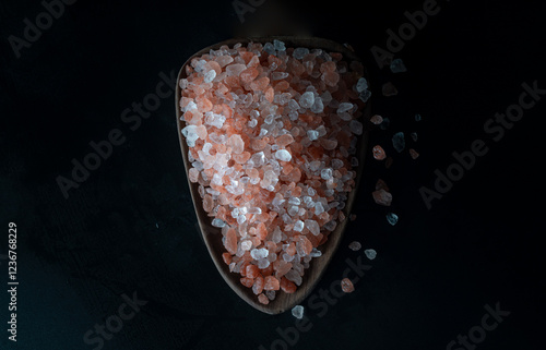 Top view of Pink Himalayan Salt with Bright colors textured surface on Wooden scoop with the dark background. Crystals and crushed blocks of natural pink salt, Chipped Himalayan salt stone, Copy space