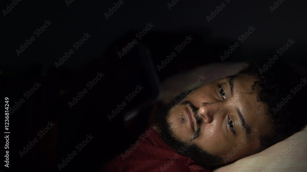 Man struggling with sleeplessness using smartphone in bed at night Man struggling with sleeplessness using smartphone in bed at night