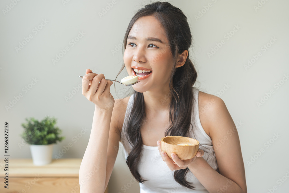 Protein in food, happy smiling asian young woman, girl in diet eat boiled egg, hand holding spoon put food in mouth with for breakfast in the morning at home. Health care, loss weight people concept. Protein in food, happy smiling asian young woman, girl in diet eat boiled egg, hand holding spoon put food in mouth with for breakfast in the morning at home. Health care, loss weight people concept.