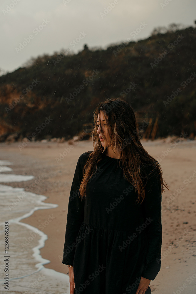 Beautiful girl walking along the beach in the rain