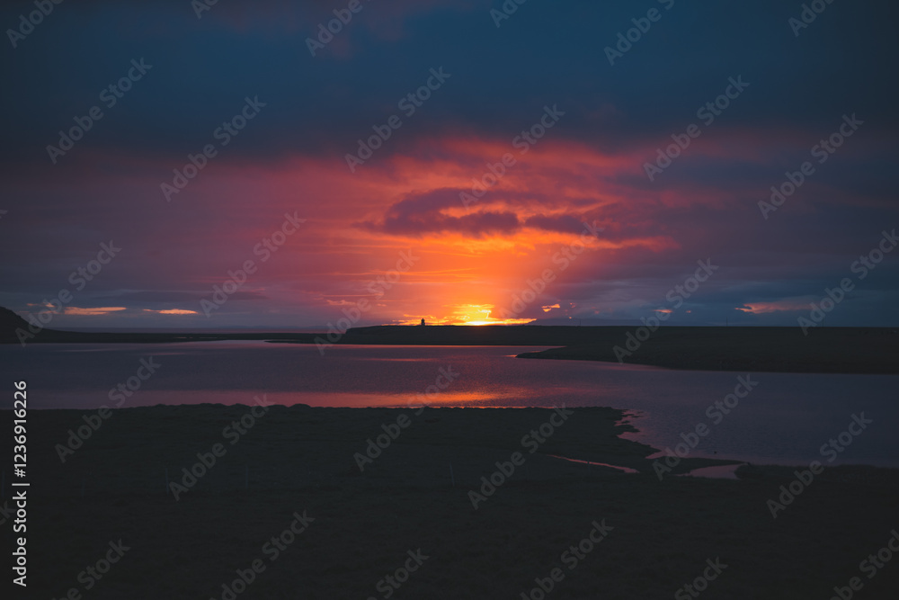 Fototapeta premium Stunning sunset on the Snaefellsnes peninsula, Iceland, with vibrant pink and purple hues reflecting perfectly on the calm water. A serene and breathtaking view near Grundarfjordur