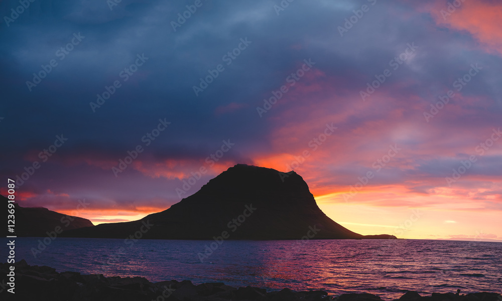 Kirkjufell mountain on the Snaefellsnes peninsula in Iceland during sunset. The iconic peak reflects over the calm waters, surrounded by vibrant colors of the evening sky Kirkjufell mountain on the Snaefellsnes peninsula in Iceland during sunset. The iconic peak reflects over the calm waters, surrounded by vibrant colors of the evening sky