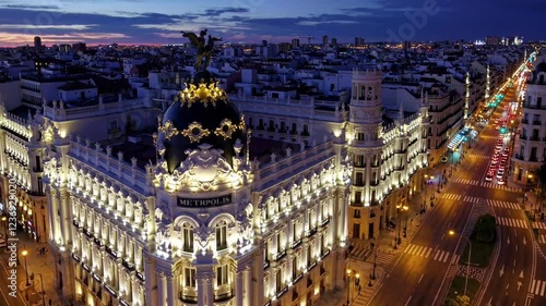A breathtaking 4K ultra-HD aerial stock video capturing the stunning Madrid city skyline at twilight, with the iconic Gran Vía street illuminated by the warm glow of streetlights and neon signs.