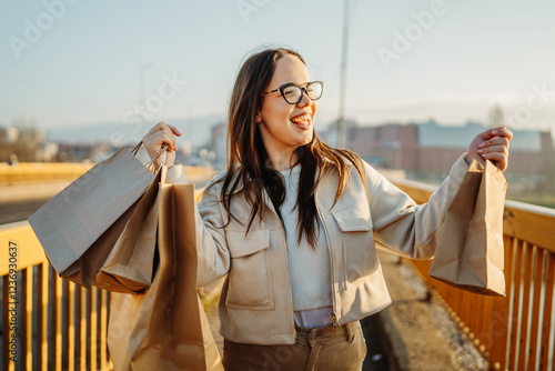 Young caucasian woman going home with full shopping bags after shopping photo