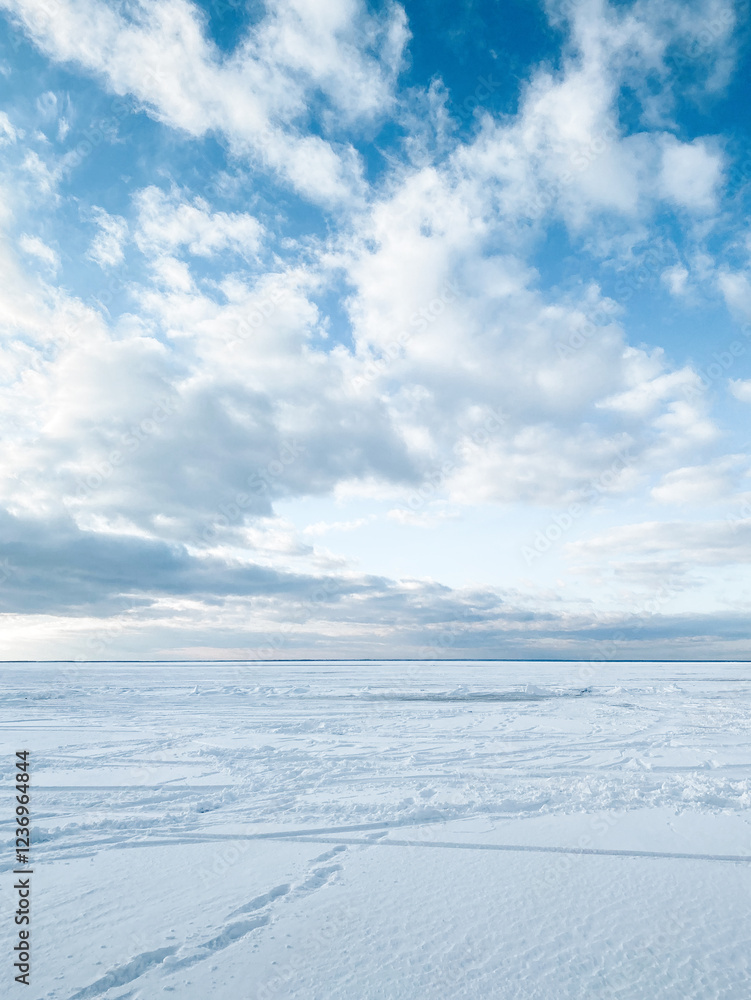 Huge frozen lake covered with thick snow. Winter seascape: clouds above the endless snow desert surface with footprints. Huge frozen lake covered with thick snow. Winter seascape: clouds above the endless snow desert surface with footprints.