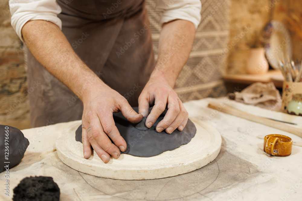 Partial shot of potter doing plate from black clay in studio Partial shot of potter doing plate from black clay in studio