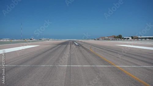 A clear view of Gibraltars airport runway, showcasing the long landing and takeoff area under a bright blue sky with minimal surroundings. photo