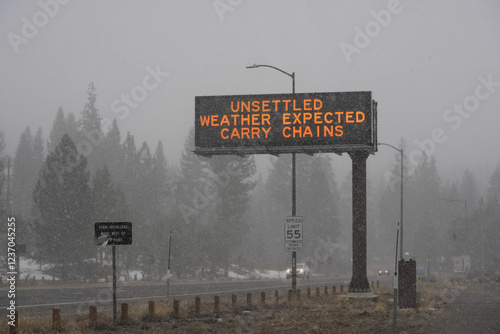 Photography Highway digital billboard during snow storm in the Sierra Nevada mountains that reads, Unsettled Weather, Carry Chains