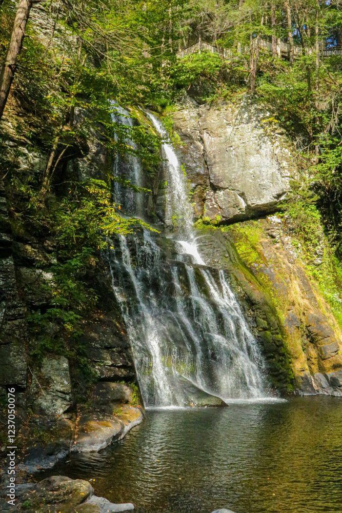 Naklejka premium Beautiful waterfall cascading into a serene pool surrounded by lush greenery. Bushkill Falls in Poconos Pennsylvania.
