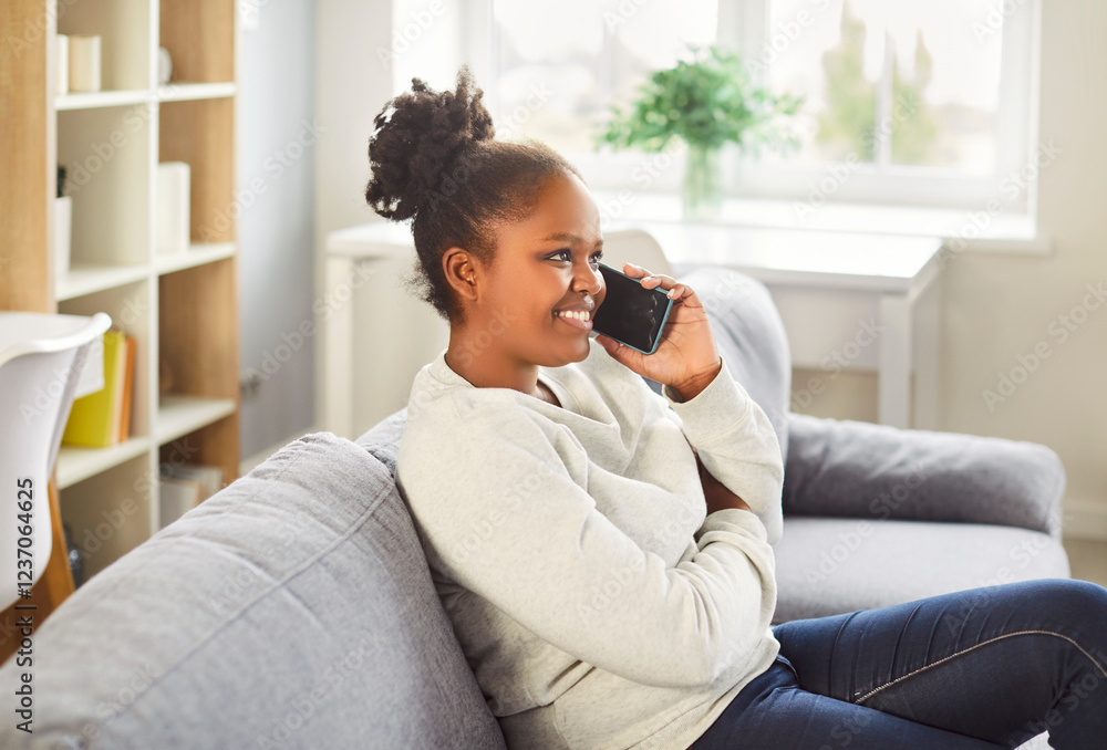 Young african american woman talking on phone at home, happy girl holding cellphone making, answering call, having pleasant conversation chatting by mobile, ordering food, chatting relaxed Young african american woman talking on phone at home, happy girl holding cellphone making, answering call, having pleasant conversation chatting by mobile, ordering food, chatting relaxed