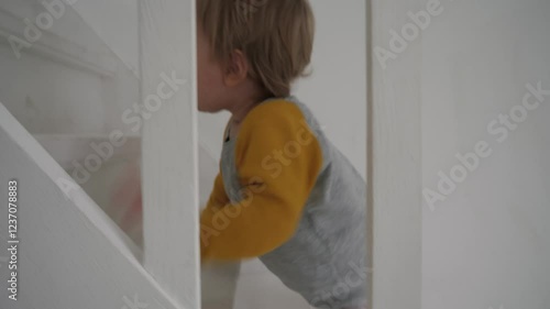 Wallpaper Mural In bright and modern home, curious and adventurous toddler climbs up the stairs, demonstrating his determination to explore. Child climbing white staircase, creating playful atmosphere Torontodigital.ca