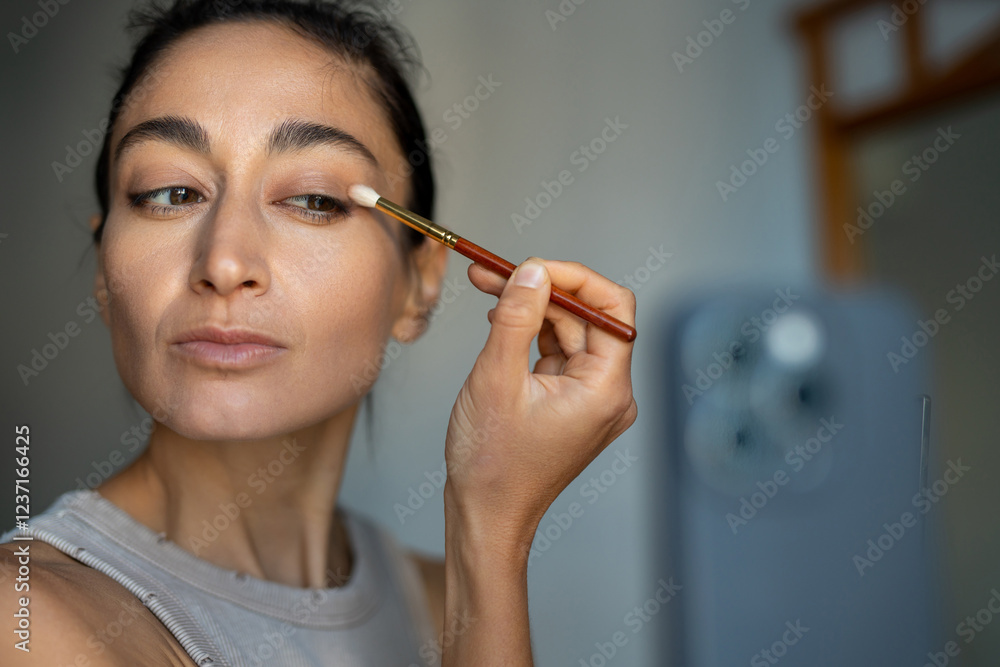 Focused Woman Applying Eyeshadow with a Brush While Filming Beauty Tutorial Focused Woman Applying Eyeshadow with a Brush While Filming Beauty Tutorial