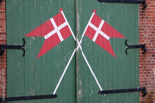 close-up of a green wooden door with painted Danish flags