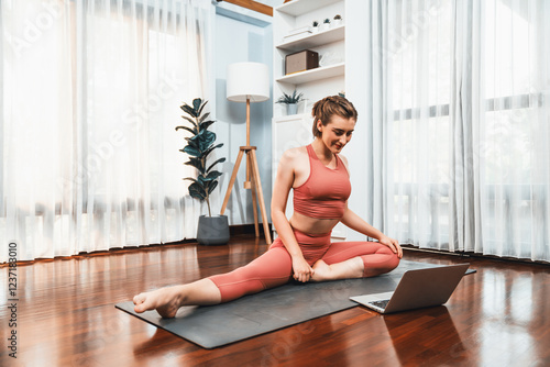 Fotografie Flexible and dexterity woman in sportswear doing yoga position in meditation posture on exercising mat at home