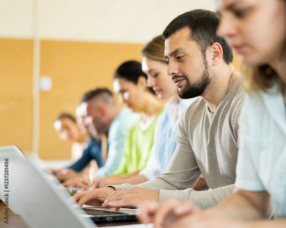 Fototapeta premium Portrait of a student guy studying on a laptop during a class in a university auditorium