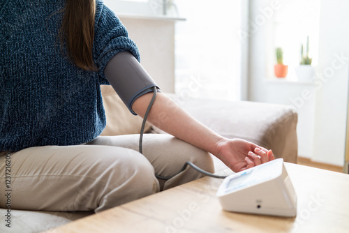 Young woman measuring blood pressure at home close up photo