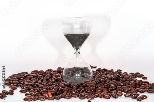 Glass Hourglass Timer with Black Sand Surrounded by Roasted Coffee Beans on a White Background photo