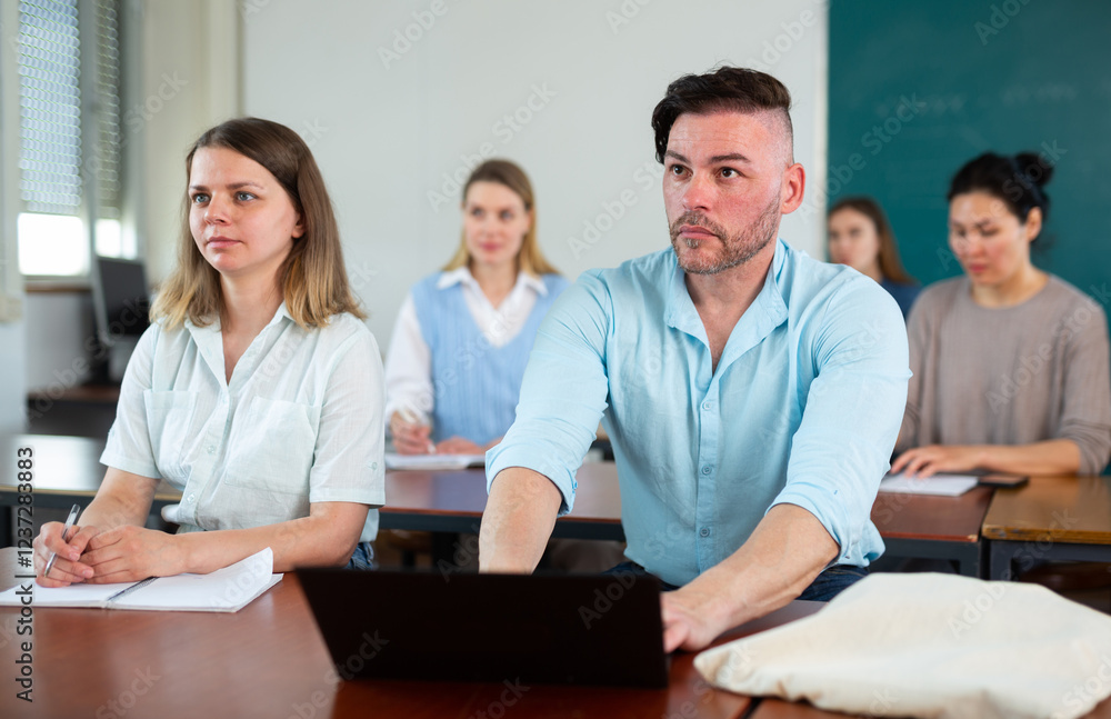 Woman and man university students sitting at table during lesson and using laptop. Woman and man university students sitting at table during lesson and using laptop.