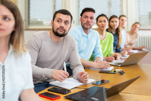 Group of attentive students studies in the university auditorium during class, writing lecture in copybooks