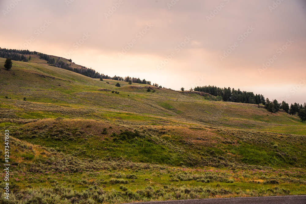 Fototapeta premium Dark clouds hover over mountain hills at sunset
