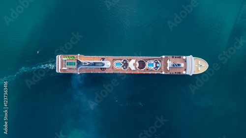 Aerial view of luxurious cruise ship sailing slowly in calm blue water as smoke pours from the chimney on the upper deck