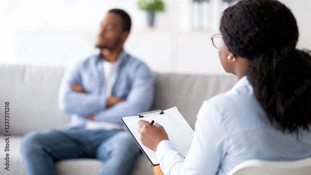 Young black man with mental problem having session with psychotherapist at medical office, selective focus. African American male patient receiving professional psychological help, copy space Young black man with mental problem having session with psychotherapist at medical office, selective focus. African American male patient receiving professional psychological help, copy space