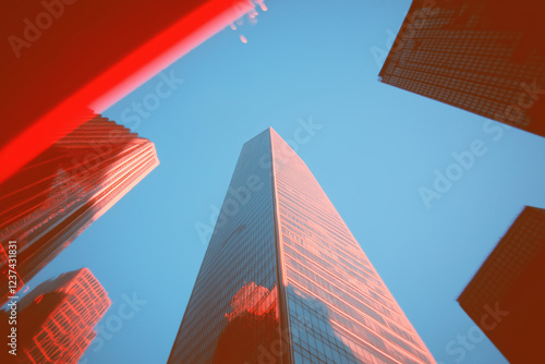 Low angle view of skyscrapers against a clear blue sky with a red filter effect