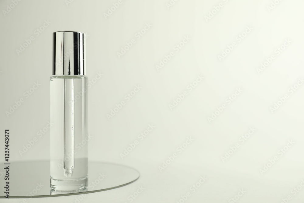 Bottle of serum and mirror on light background, space for text Bottle of serum and mirror on light background, space for text