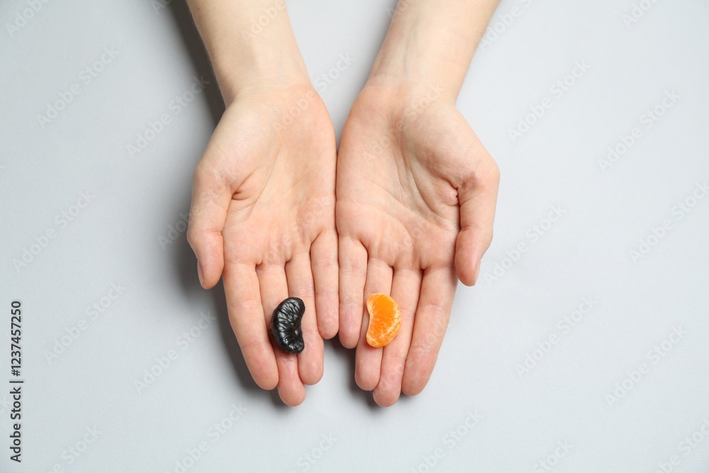 Woman with tangerine segments of different colors on light grey background, top view Woman with tangerine segments of different colors on light grey background, top view