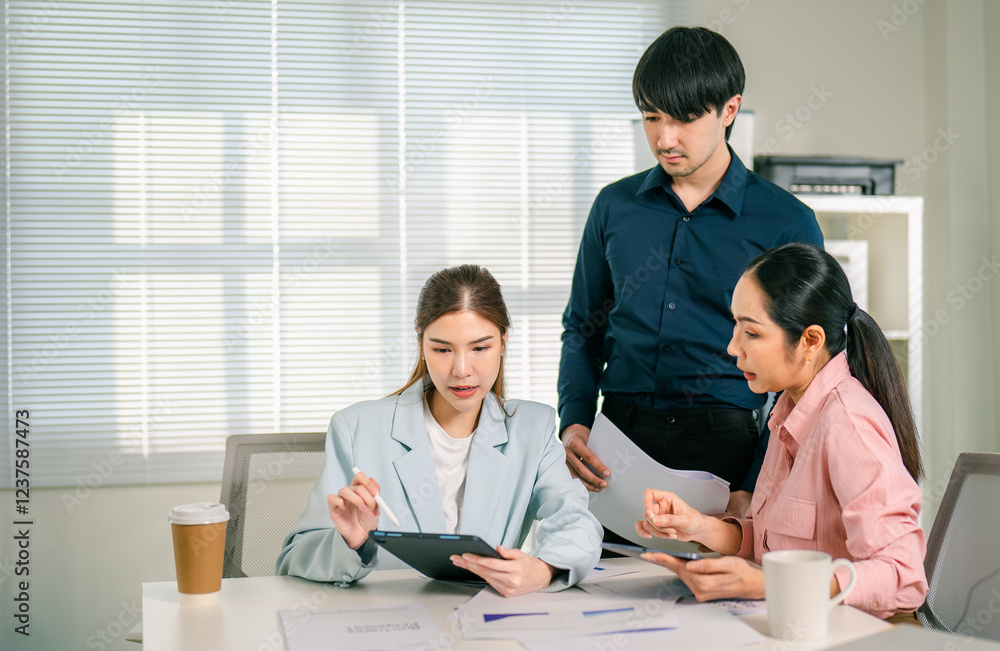 Three professionals collaborate in a bright office, discussing documents and reviewing information on a tablet, showcasing teamwork and engagement. Three professionals collaborate in a bright office, discussing documents and reviewing information on a tablet, showcasing teamwork and engagement.