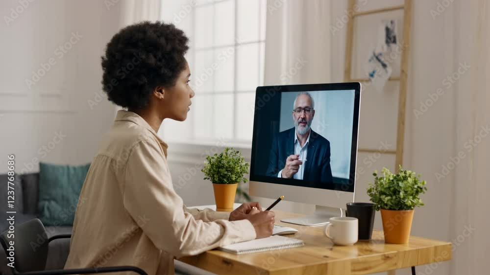African American adult student having virtual meeting online call educational webinar chatting with senior teacher at home office writing notes. Remote working online.