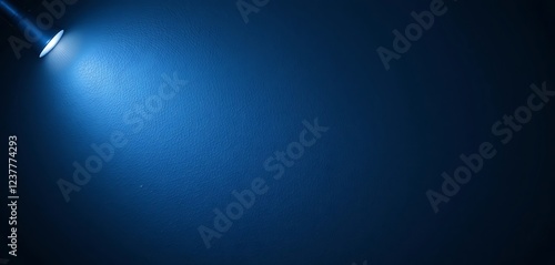 Blue textured wall lit by a flashlight, creating a dramatic spotlight effect, dark blue background, textured wall, spotlight, dark background, dramatic lighting