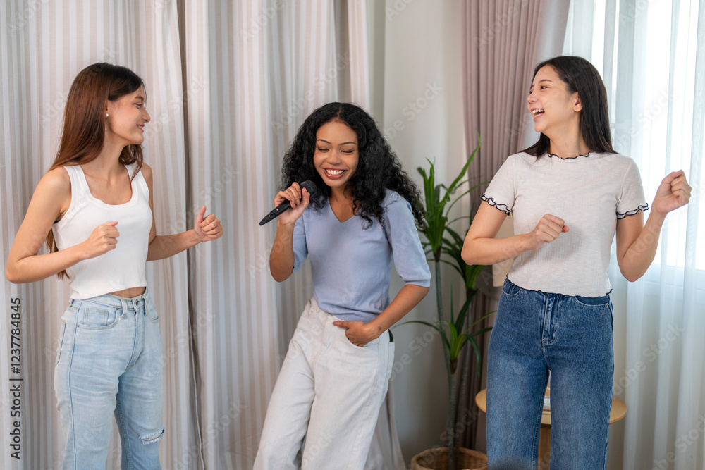 Diverse group of female friends singing together with microphone enjoying a fun and cheerful moment at home, dancing, smiling and celebrating friendship in a casual indoor with music and laughter Diverse group of female friends singing together with microphone enjoying a fun and cheerful moment at home, dancing, smiling and celebrating friendship in a casual indoor with music and laughter