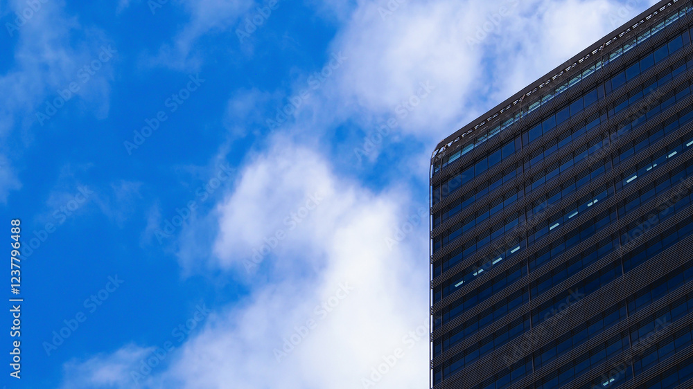 A striking juxtaposition of a modern glass building against a vibrant blue sky with soft clouds. Perfect for corporate branding, urban photography showcases, or architectural simplicity concepts. A striking juxtaposition of a modern glass building against a vibrant blue sky with soft clouds. Perfect for corporate branding, urban photography showcases, or architectural simplicity concepts.