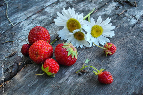 Wild Strawberries and Daisies on Rustic Wooden Surface photo