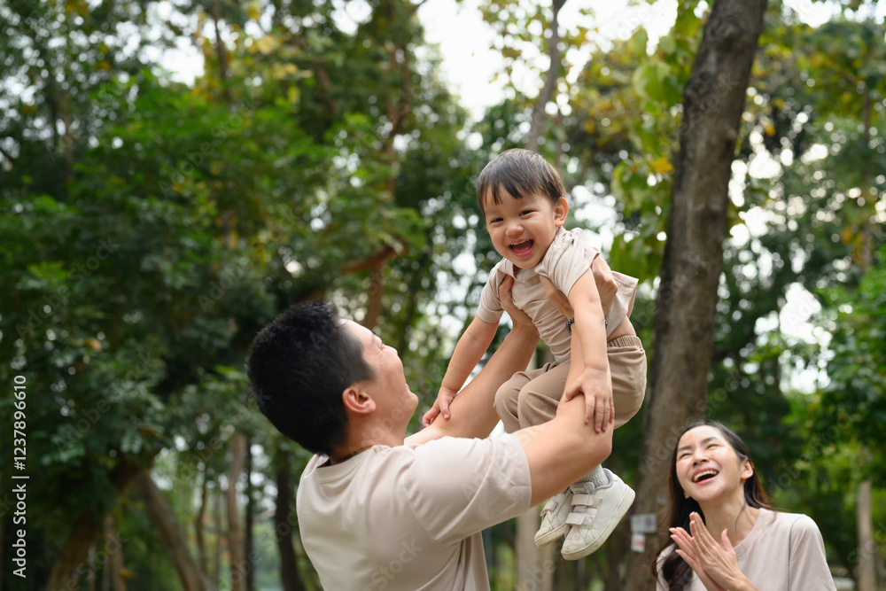 Happy father lifting his laughing son in the air. Outdoor leisure and family bonding concept Happy father lifting his laughing son in the air. Outdoor leisure and family bonding concept