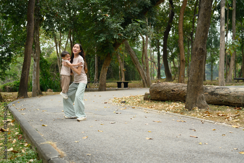 Loving mother playing with her little son on a walking path in a beautiful park Loving mother playing with her little son on a walking path in a beautiful park