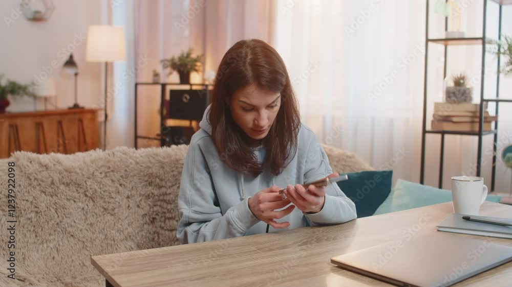 Young frustrated woman plugging charging cable into smartphone and unplugging it repeatedly as charger fails to work. Girl appears frustrated noticing cable is broken and unable to charge device. Young frustrated woman plugging charging cable into smartphone and unplugging it repeatedly as charger fails to work. Girl appears frustrated noticing cable is broken and unable to charge device.