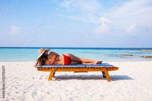 Woman relaxing on lounge chair on the beach, Maldives photo